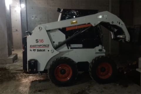 Bobcat Skid-Steer Loader backfilling dirt in a basement.