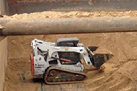 Bobcat Compact Track Loader pusing dirt on a cargo ship