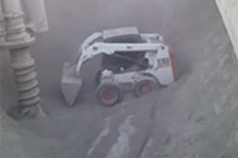 Bobcat skid-steer loader uses attachments to break up cement on a cargo ship.