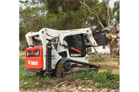 Bobcat S770 Skid-Steer Loader with root grapple attachment carrying trees