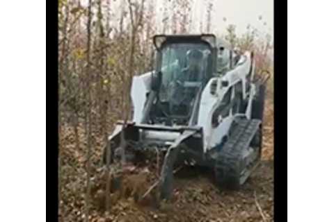 Bobcat Compact Track Loader with Digger attachment planting a tree.